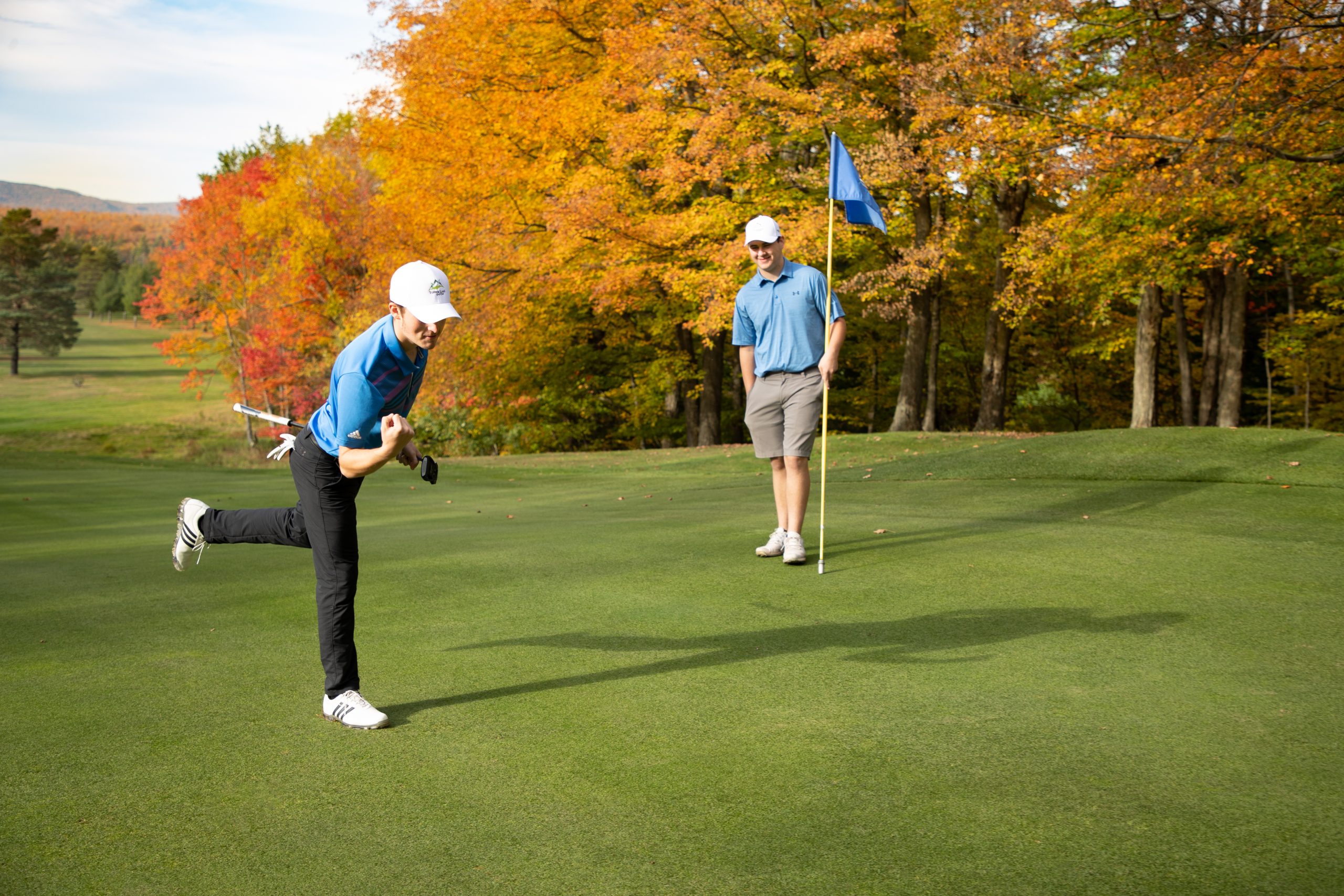 Golfer sinks a long putt on 15 green with fall foliage